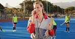 Coach, hockey field and woman with phone call for match organization, conversation and event info.Planning, mobile and sport trainer with clipboard on turf, game arrangement and local league opponent