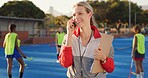 Coach, hockey turf and woman with phone call for match organization, conversation and event info.Planning, mobile and sport trainer with clipboard on field, game arrangement and local league opponent