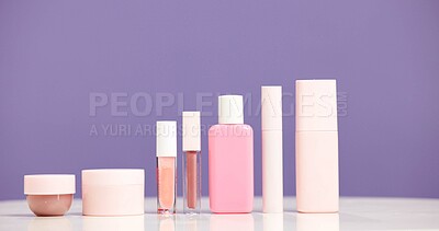 Buy stock photo Makeup, bottles and product selection in studio for beauty aesthetic, skincare routine and marketing. Space, container or cosmetic range for dermatology, wellness or advertising on purple background.