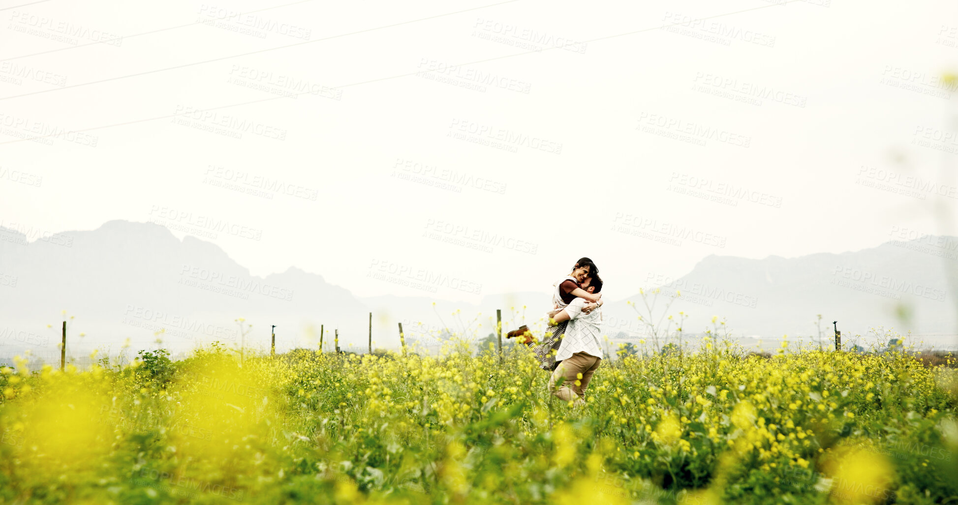 Buy stock photo Love, couple and hug on field on vacation, care or romance for connection with space. Embrace, man and happy woman in countryside with flowers on holiday, anniversary celebration and together outdoor