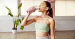 Fitness, drinking water and woman in yoga studio, indoor exercise and hydration on workout break. Thirsty, refreshing liquid and person gulp from bottle for recovery, pause and rest in health club.