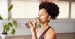 Fitness, water break and woman drinking in studio, indoor exercise and yoga workout for thirst. Hydration, refreshing liquid and person gulp from bottle for recovery, pause and rest in health club.