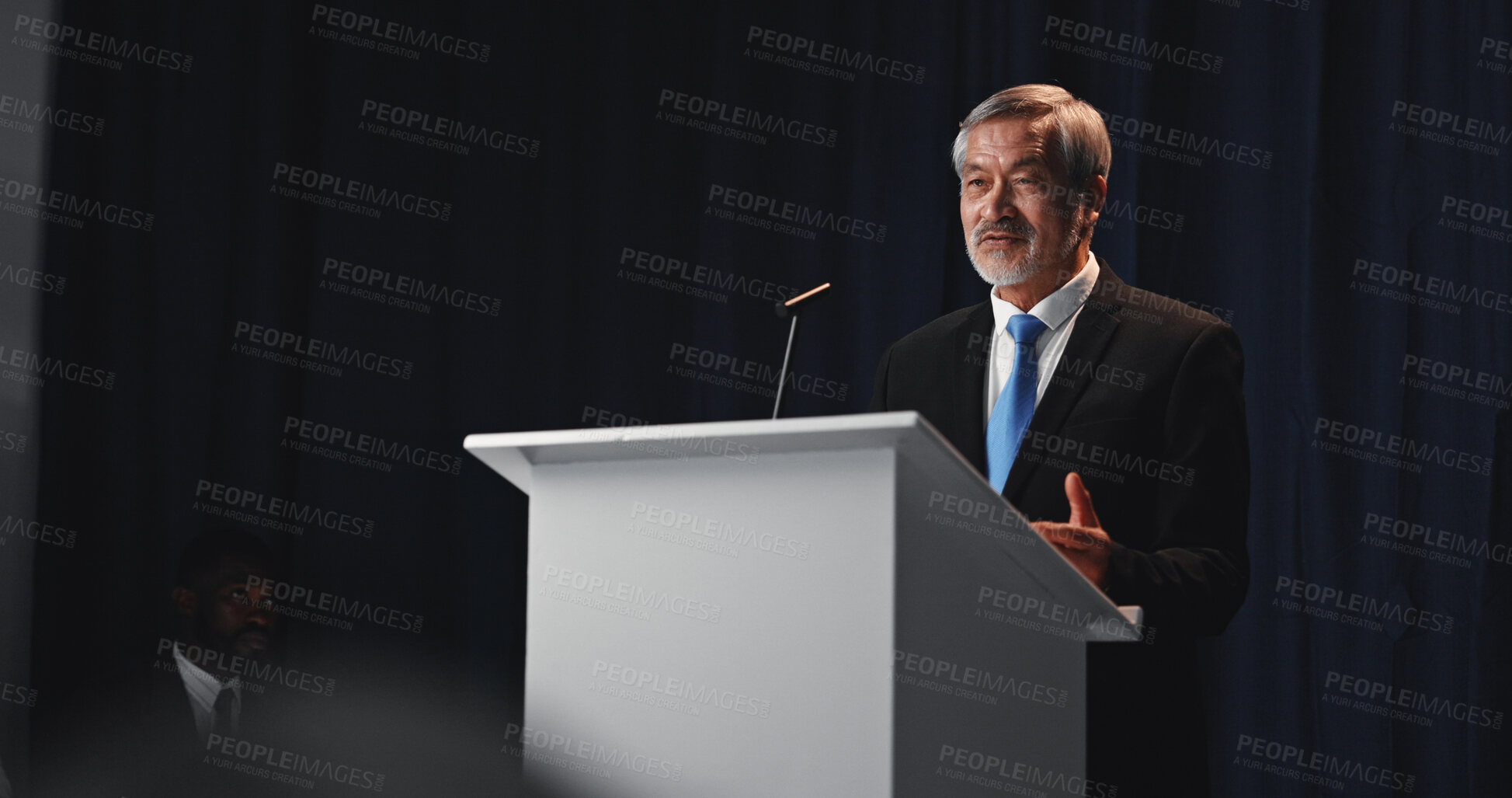 Buy stock photo Speaker, mature man and politician with mic for election, democracy or political campaign. Speech, greeting and podium at conference, meeting or seminar event for vote or activism at convention