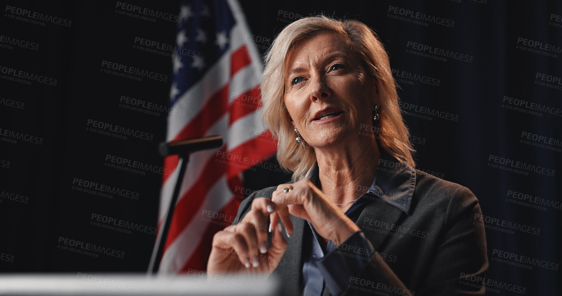 Buy stock photo Politician, speech and woman with American flag with mic for election, debate or voting campaign. Government, candidate and mature person on stage for press conference, political event or delegation