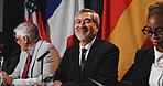 Man, flags and portrait on panel at conference, happy and pride with international delegation for peace. Mature person, politician and global leader with group, smile or negotiation for war ceasefire