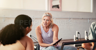 Buy stock photo Pilates, conversation and women in studio on tablet for fitness advice, workout tips or exercise. Health club, instructor and people on digital tech, chat or talking on reformer machine for wellness
