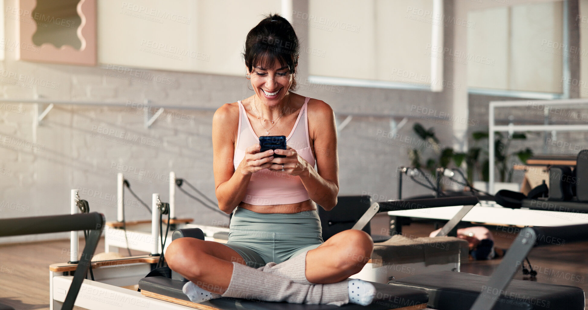 Buy stock photo Phone, reformer machine and woman at pilates class for fitness with networking, contact or texting. Happy, equipment and female person with cellphone for communication, chatting or social media.