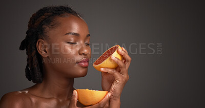 Buy stock photo Black woman, skincare and smell grapefruit in studio, mockup space and vitamin c on dark background. African person, citrus fruit and thinking with scent, organic product and benefits with beauty