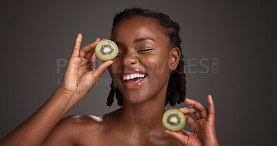 Buy stock photo Skincare, laugh and black woman in studio with kiwi for organic cosmetics, wellness and collagen. Dark background, spa and person with fruit for natural beauty, vitamin c and dermatology benefits