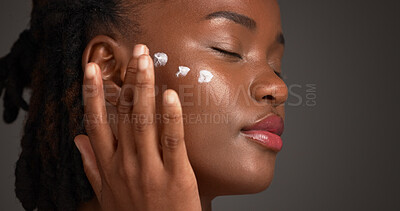 Buy stock photo Black woman, studio and skincare with lotion for moisturizer or face cream on a gray background. Female person, model or applying product with beauty cosmetics for anti aging or soft skin on space
