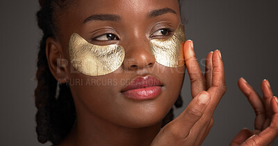 Buy stock photo Face, skincare and black woman in studio with eye mask for anti aging, dark circles and wellness. Dermatology, gold and person with pads for circulation, hydration and beauty on gray background