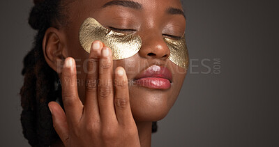 Buy stock photo Beauty, eye patch and facial with black woman on studio space for cosmetics or dermatology. Apply, gold product and skincare with African model isolated on gray background for antiaging treatment