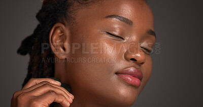 Buy stock photo Black woman, skincare and spa with gua sha for anti aging or massage on a gray studio background. Female person, model or relaxation with beauty tool for collagen, lymphatic drainage or dermatology
