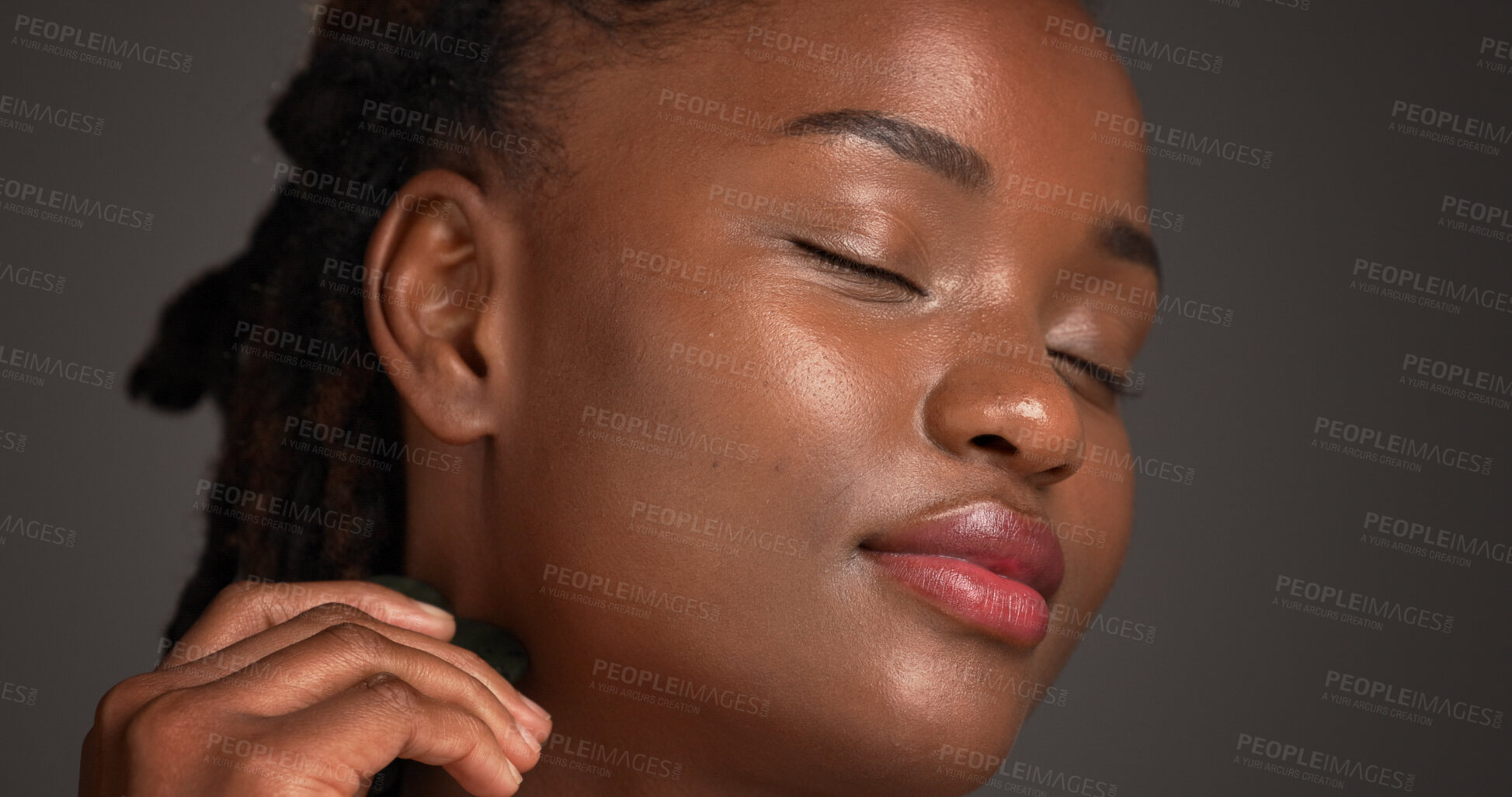 Buy stock photo Black woman, skincare and spa with gua sha for anti aging or massage on a gray studio background. Female person, model or relaxation with beauty tool for collagen, lymphatic drainage or dermatology