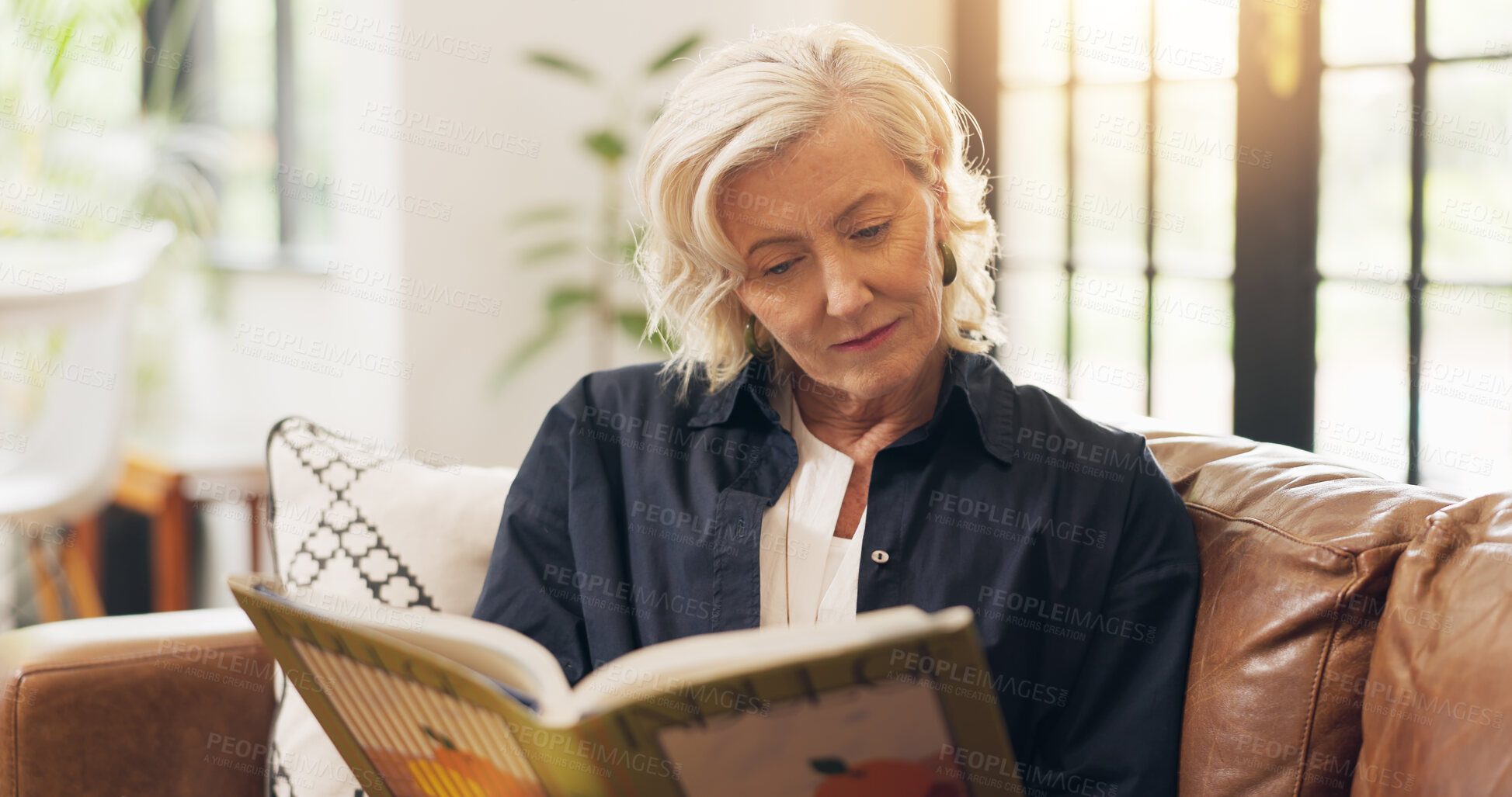 Buy stock photo Senior woman, reading book and happy on sofa, relax and literature in living room at apartment. Person, smile and novel on couch in lounge for learning, poetry or fiction story with flare at house