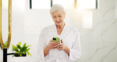 Buy stock photo Smile, woman and reading with phone in bathroom for morning news, texting and scroll social media. Robe, home and mature person with mobile app for online search, communication or check notifications