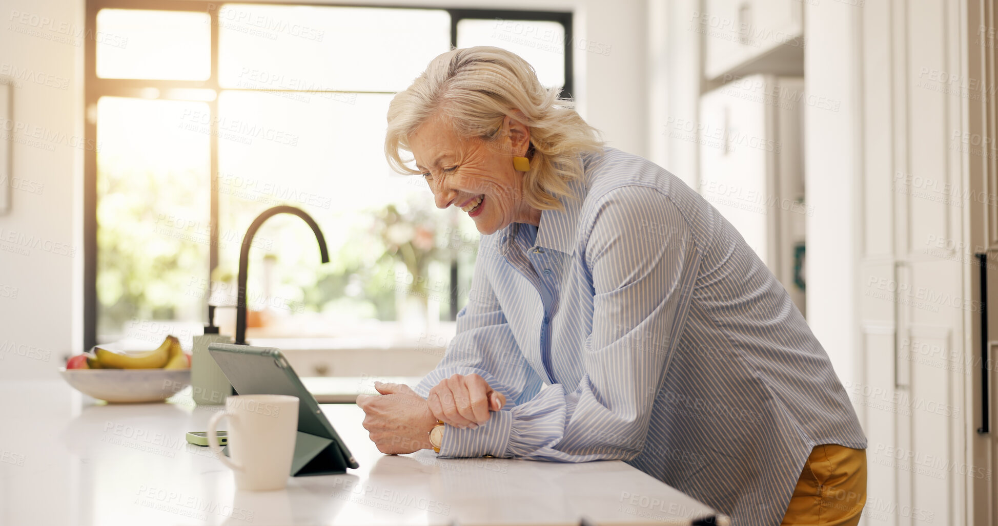 Buy stock photo Smile, senior woman and tablet in kitchen for research, social media and reading funny meme. Happy, elderly person and laugh with digital, comedy video and streaming online for entertainment at house