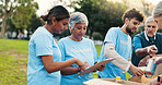 Woman, volunteer and planning with clipboard at park for donation, point and writing for social responsibility. People, team and help with checklist, review or talk with sign up for charity event