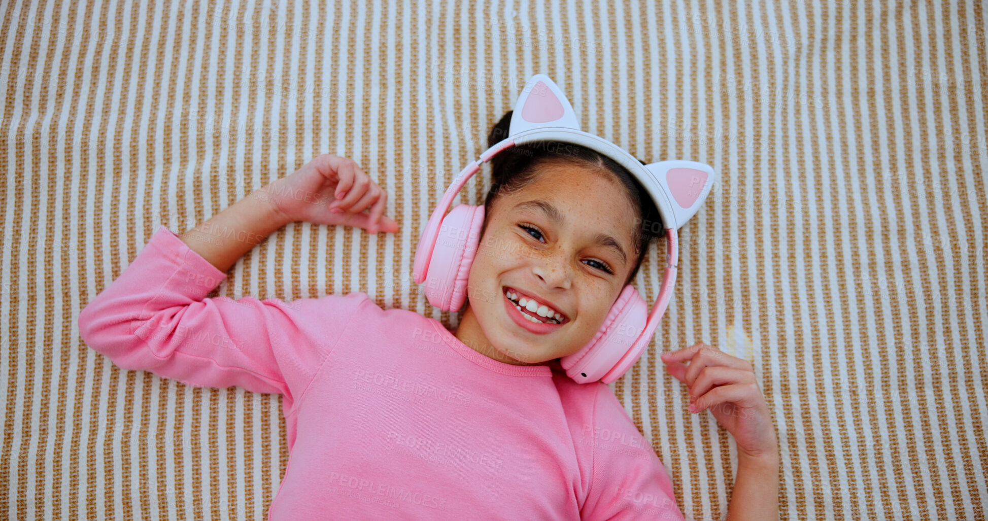 Buy stock photo Portrait, headphones and happy kid on bed for music, streaming service and relax above. Smile, top view and girl in bedroom for audio, online radio and child listening to sound on weekend in home