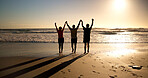 Arms up, silhouette and people at beach with sunset, connection or celebration in trip success. Back, holding hands or friends at ocean with flare, adventure or travel achievement in summer evening.