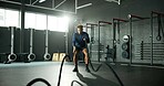 Man, battle rope and workout in gym for cardio, exercise and body building for fitness. Intense routine, muscle and wellness with power for strength training, weight equipment and bicep challenge