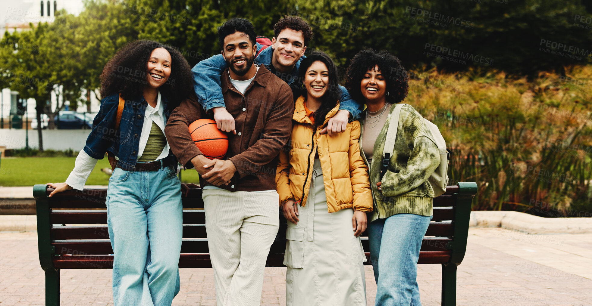 Buy stock photo Portrait, friends or college student with hug by bench on campus, education support or outdoor on study break. Embrace, diversity and happy people bonding together, care and knowledge with basketball