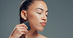 Woman, gua sha or massage in studio with skincare for beauty, dermatology or facial tension. Relax, female person or cosmetic tool for lymphatic drainage, wellness or mockup space on gray background.