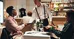 Waiter, couple and order at restaurant with menu, decision and discussion for wine list, food or service. People, server and talk for customer experience, thanks and happy with dinner choice at night