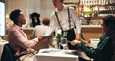 Buy stock photo Waiter, couple and order at restaurant with menu, decision and discussion for wine list, food or service. People, server and talk for customer experience, thanks and happy with dinner choice at night