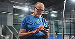 Padel, senior man and texting with phone on court for match update, track performance or game break. Retirement fitness, old person and smartphone at indoor tennis club for practice schedule and chat