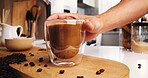 Hand, beans and glass of coffee in kitchen in home for morning brew for energy boost drink. Ingredients, espresso and person with caffeine beverage for latte in mug for liquid on counter in apartment