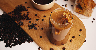 Buy stock photo Splash, coffee and glass on table in kitchen of home for caffeine beverage, breakfast and morning brew. Cappuccino, iced latte drink and prepare with above of cup in apartment for liquid and beans