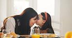 Happy mom, child and kiss with breakfast in home for love, care or bonding together on dining table. Mother, kid or daughter with orange juice or croissant for embrace, morning meal or snack in house