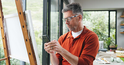 Buy stock photo Painting, phone and search with man in home for design reference, artist project and contact. Creative inspiration, artwork and canvas with mature person  and tech in apartment studio for hobby