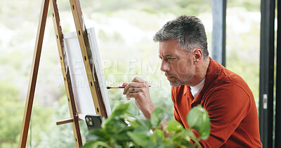 Buy stock photo Mature man, painting and art with easel, frame or paintbrush for drawing or sketching in home. Male person, artistic or creative painter with brush or color for artwork, skill or talent in house