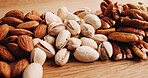 Closeup, kitchen and nuts on table for diet, vegan meal and healthy snack for nutrition. Counter, seed production and roasted pistachios, almonds and pecan for organic food, natural fats and protein
