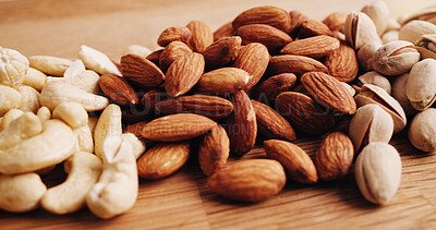 Buy stock photo Closeup, kitchen and nuts on counter for diet, vegan meal and healthy snack for nutrition. Table, seed production and roasted pistachios, almonds and cashews for organic food, natural fats or protein