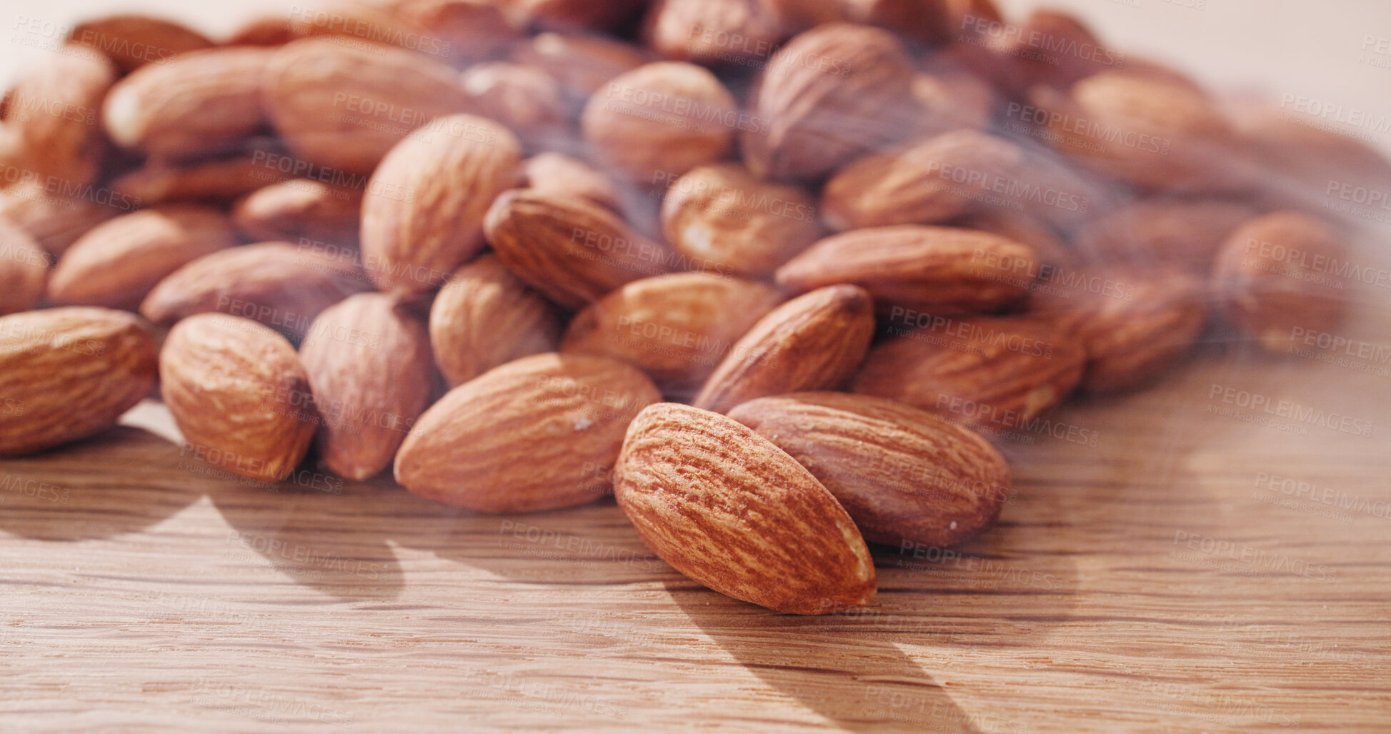 Buy stock photo Table, nuts and roasted almonds for diet, vegan meal or healthy snack for nutrition. Kitchen counter, food production and closeup of seeds with smoke for organic benefits, natural vitamins or protein