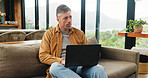 Thinking, laptop and mature man on sofa for online article, website research and proofreading. Freelancer, living room and person on computer for editing report, story review and remote work in home