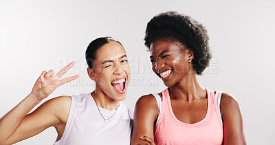 Buy stock photo Peace sign, fitness and portrait of women in studio with confidence for exercise, training and workout. Wink, athletes and happy friends with emoji for wellness, pride and health on white background
