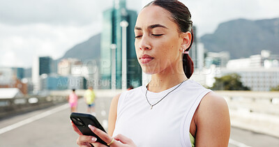 Buy stock photo Woman, runner and phone with fitness in city, bridge and break with notification, texting and training. Person, smartphone and scroll on mobile app with search for exercise tips in town with routine