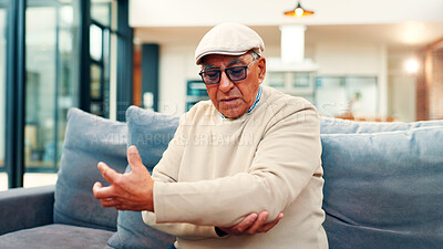 Buy stock photo Elbow pain, home and senior man on sofa with injury for arthritis, osteoporosis and fibromyalgia. Retirement, living room and mature person with discomfort for inflammation, joint ache and tension