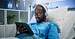 Black man, headphones and relax with tablet in hospital bed for streaming music, movies and recovery. Male person, inpatient and digital for listening to audio, watching film and healing of operation