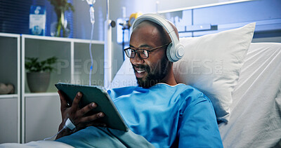 Buy stock photo Black man, headphones and relax with tablet in hospital bed for streaming music, movies and recovery. Male person, inpatient and digital for listening to audio, watching film and healing of operation
