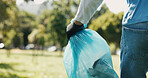 Hands, person and volunteer with plastic bag outdoor for cleaning, trash collection and park cleanup. Worker, helping and garbage for waste management, community service and recycling for earth day