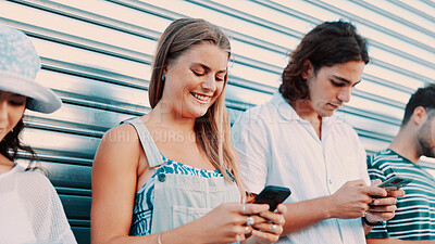 Buy stock photo Phone, smile and typing with people outdoor together for connection or social media browsing. App, contact and text message with group of happy friends in line for communication or online chat