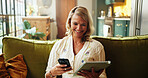 Phone, smile and tablet with woman on sofa in living room of home to search for holiday review. App, reading and typing with happy person in apartment for online booking of vacation accommodation
