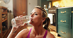 Woman, drinking water and fitness in home, break and hydration for gut health, recovery and training. Person, bottle and exercise at house, floor or rest with electrolytes for wellness in kitchen