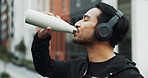 Fitness, athlete and man drinking water in city for running, exercise or endurance training. Sports, hydration and male runner with liquid for cardio, sport or workout in town with headphones