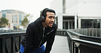 Headphones, athlete and break with running in city for workout rest, breathing or sweat with challenge. Runner, man and technology for training, fitness and exercise with podcast or streaming music